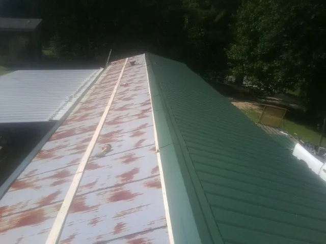 Old rusted panels beside newly installed green metal roofing — Wind Damage Roof Repair by Roofing Brothers in Jewett City