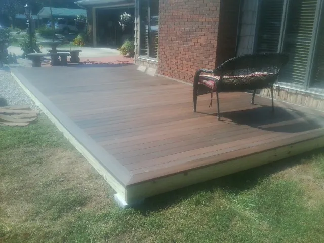 New wood deck and wicker chair beside a brick house in Jewett City