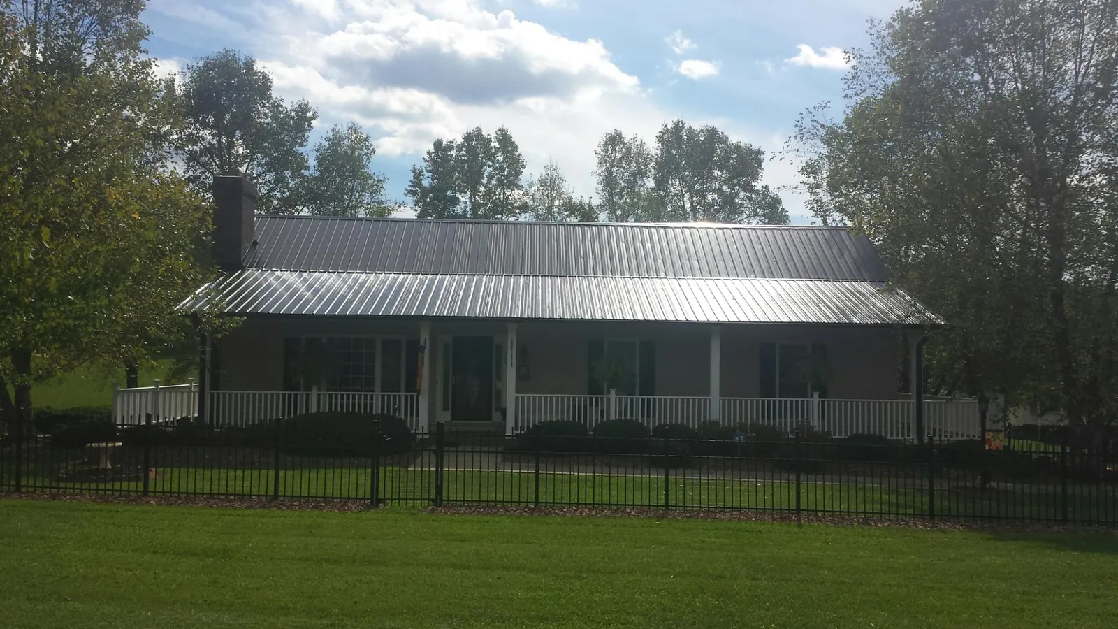 Gray metal roof on a brick ranch with a full width front porch — Gutter Guard Installation work by our crew in Jewett City