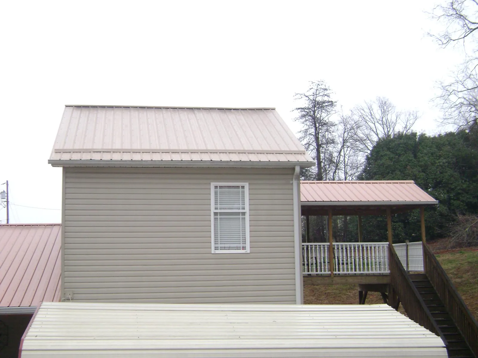 Tan metal roofs on a two story addition and attached porch, from a Roof Replacement job in Jewett City