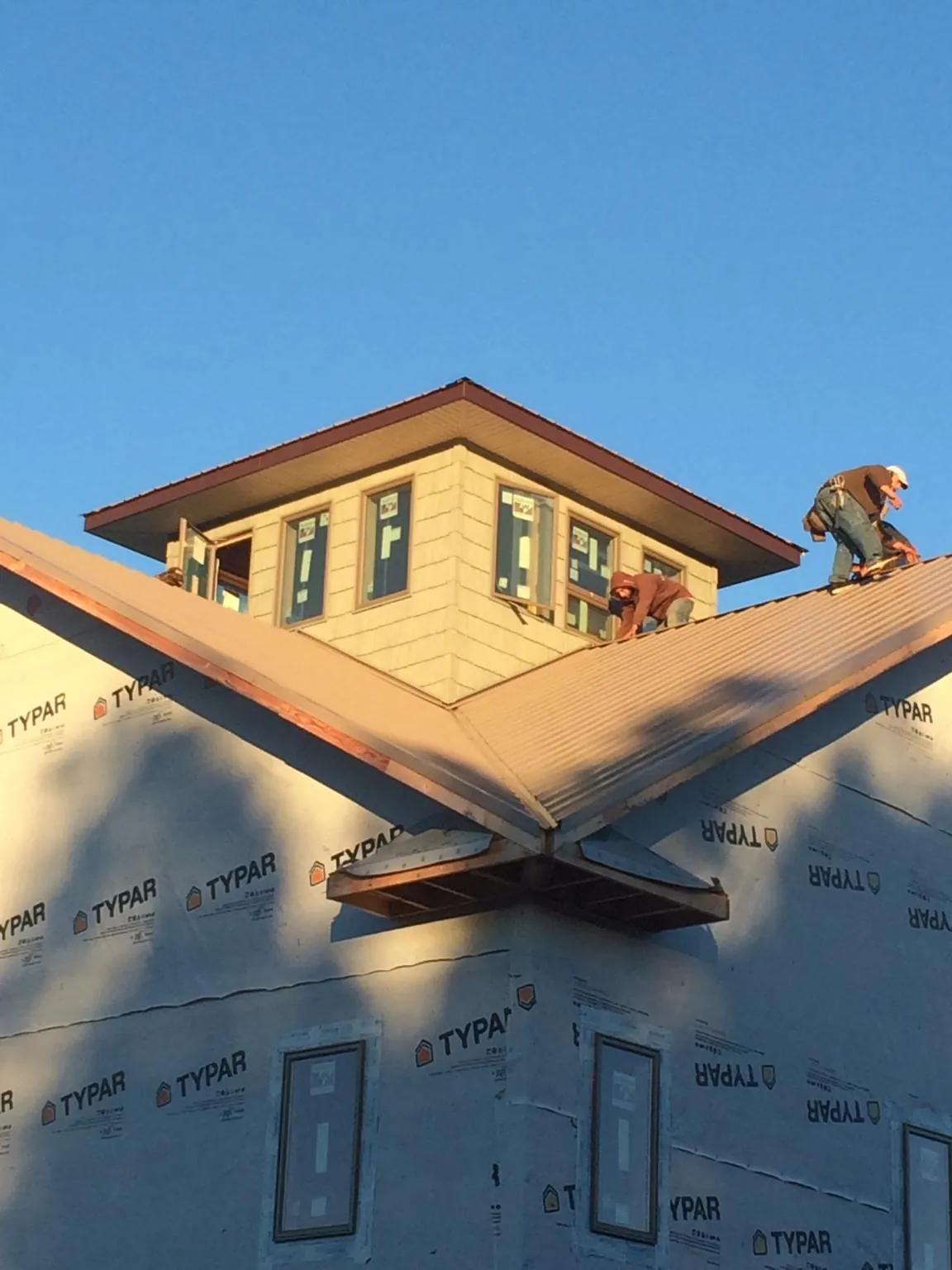 Roofers working around a rooftop cupola on a new metal roof at sunset — Roof Waterproofing in Jewett City by Roofing Brothers